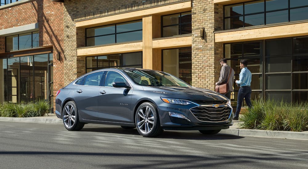 A grey 2020 Chevy Malibu is shown parked on the side of a city street.