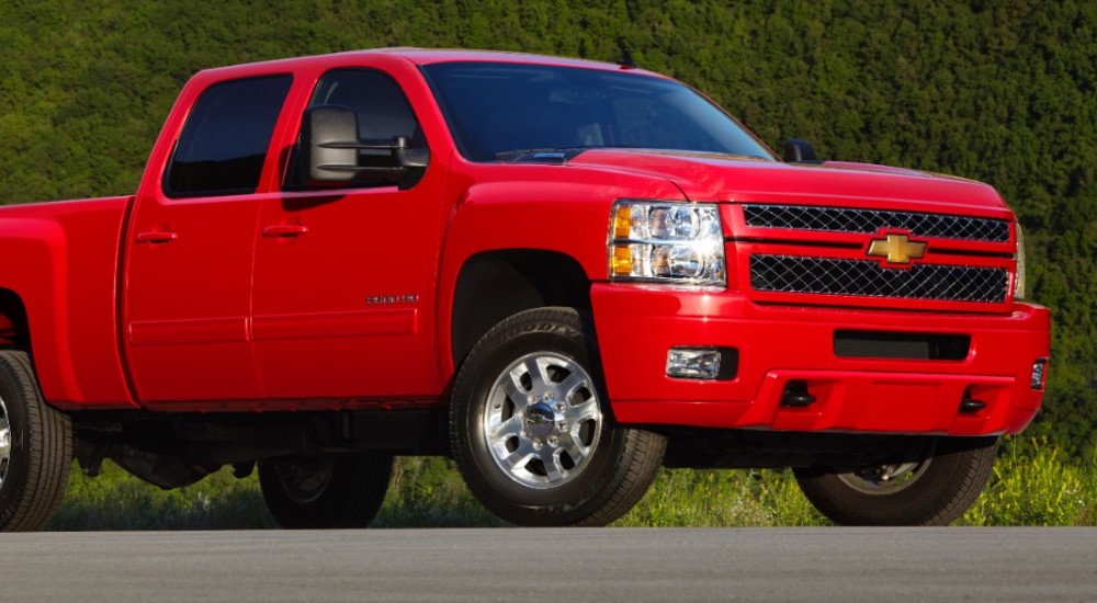 A red 2011 used Chevy Silverado 1500 LTZ near you is shown parked in an empty lot.
