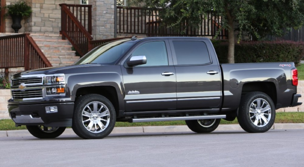 A grey 2014 Chevy Silverado 1500 High Country is shown parked on the side of a city street.