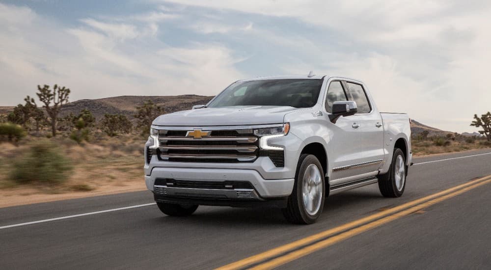 A white 2023 Chevy Silverado High Country is shown from the front at an angle.