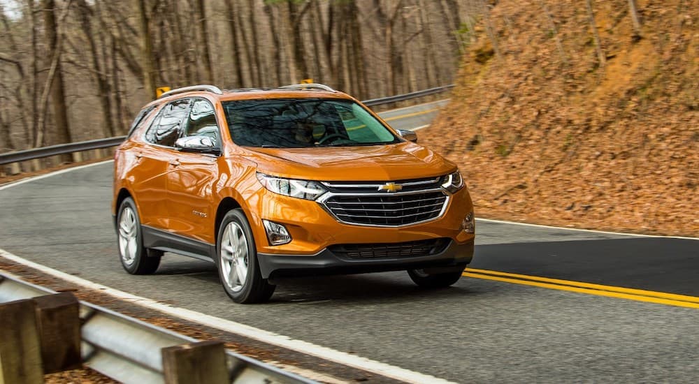 An orange 2019 Chevy Equinox is shown from the front at an angle after leaving a dealer that has used SUVs for sale.