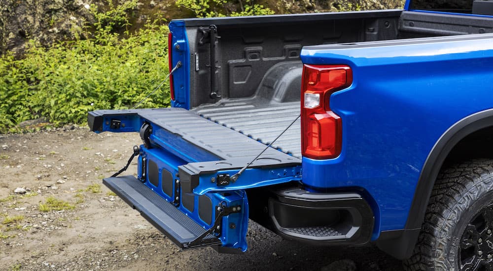 The bed of a blue 2024 Chevy Silverado 1500 is shown from the rear at an angle with the tailgate open.