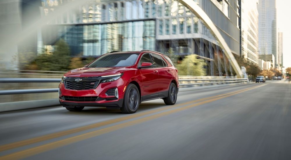 A red 2024 Chevy Equinox RS is shown driving on a bridge after leaving a Houston Chevy dealer.