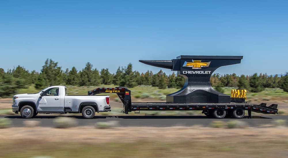 A white 2020 Chevy Silverado 3500 HD is shown from the side while towing a giant anvil.