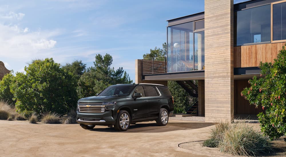 A green 2023 Chevy Tahoe High Country is shown from the front at an angle while parked in a driveway after leaving a dealer that has a Chevy Tahoe for sale.