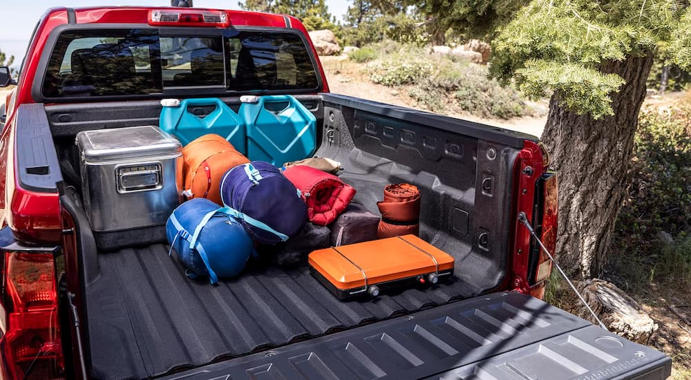 Camping gear in the open bed of a red 2024 Chevy Colorado Trail Boss.