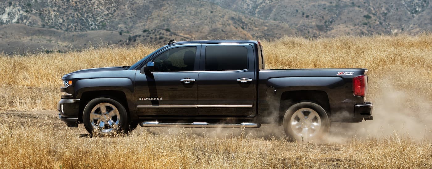 A dark blue 2018 Chevy Silverado 1500 is shown from the side in a field.