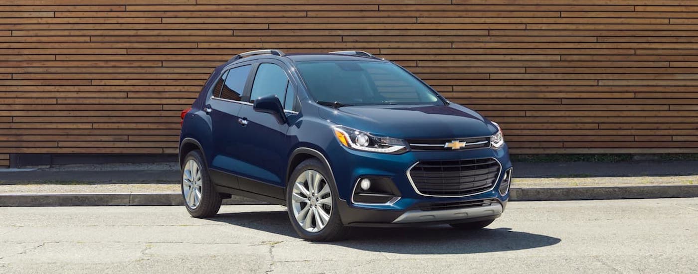 A blue 2019 Chevy Trax is parked in front of a wood wall.