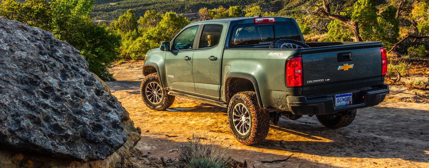 A green 2020 Chevy Colorado is shown from the rear parked on a dirt trail.