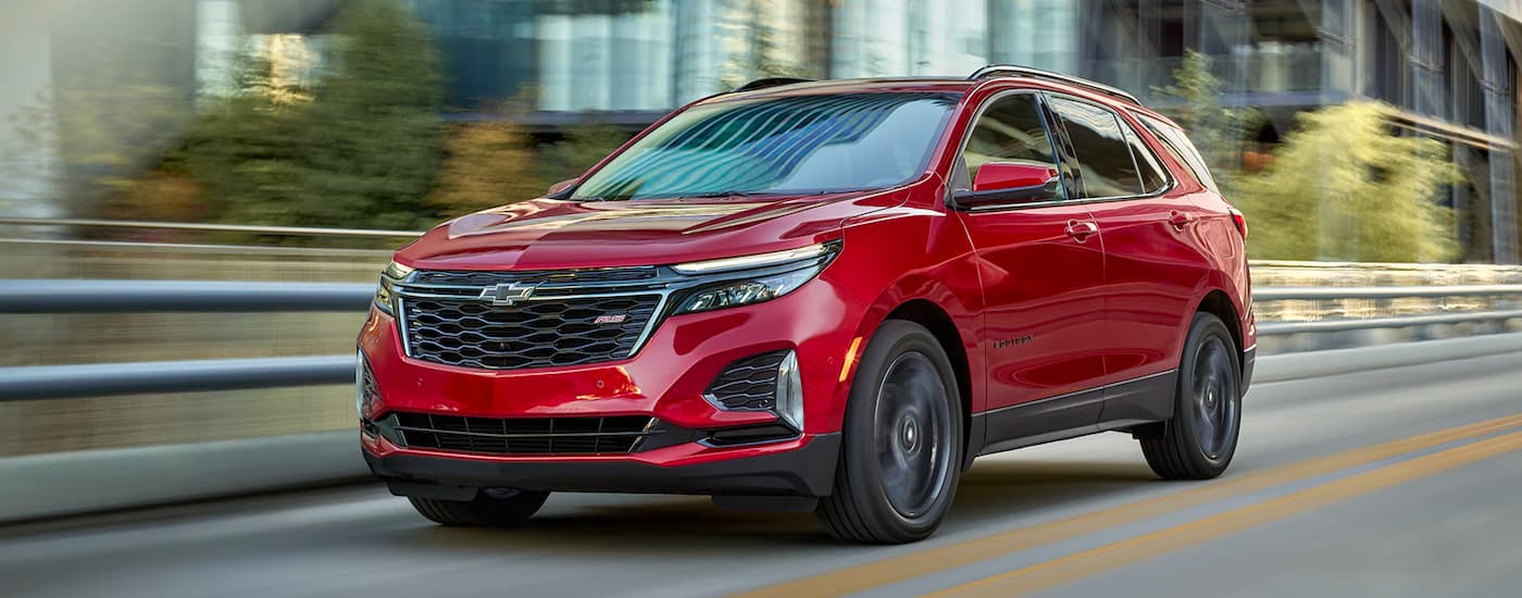 A red 2022 Chevy Equinox RS is shown driving down a city street.