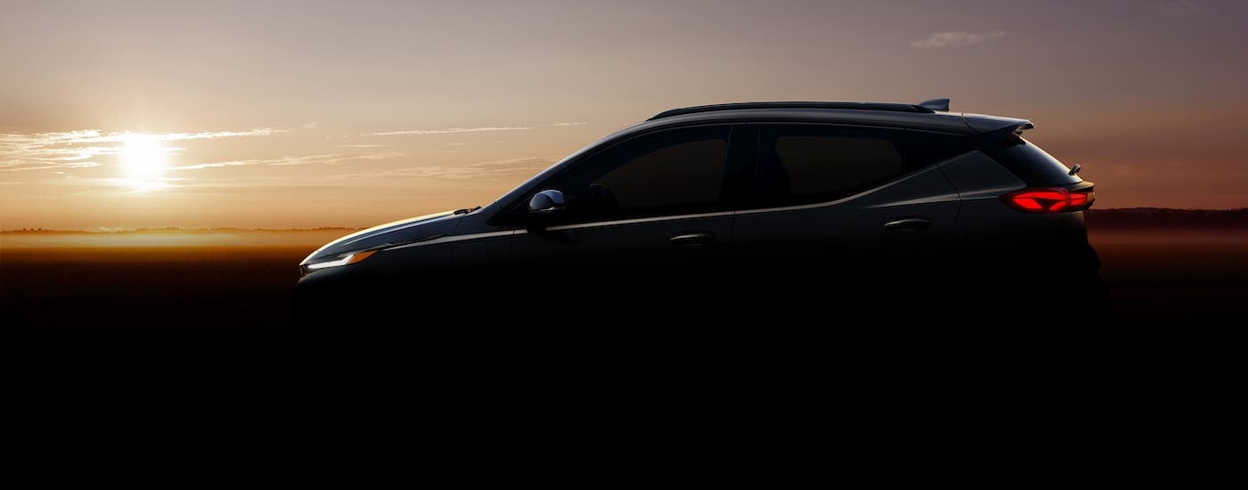 The silhouette of a 2022 Chevy Bolt EUV in front of a sunset.