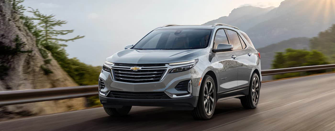 A grey 2023 Chevy Equinox is shown driving on an open highway.