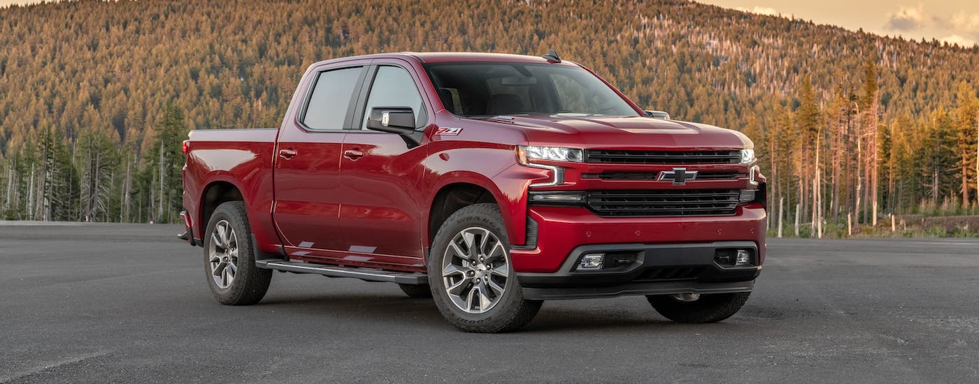 A red 2021 Chevy Silverado 1500 diesel is parked in an empty lot in front of a mountain.