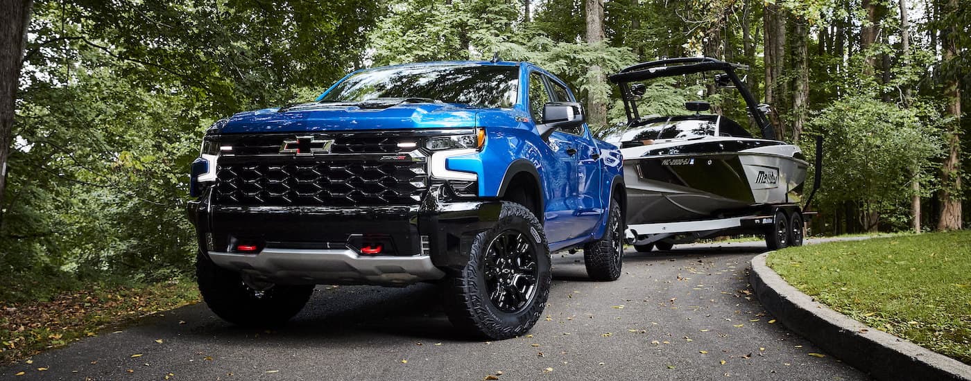 A blue 2022 Chevy Silverado 1500 ZR2 is shown from the front with a boat on a trailer.