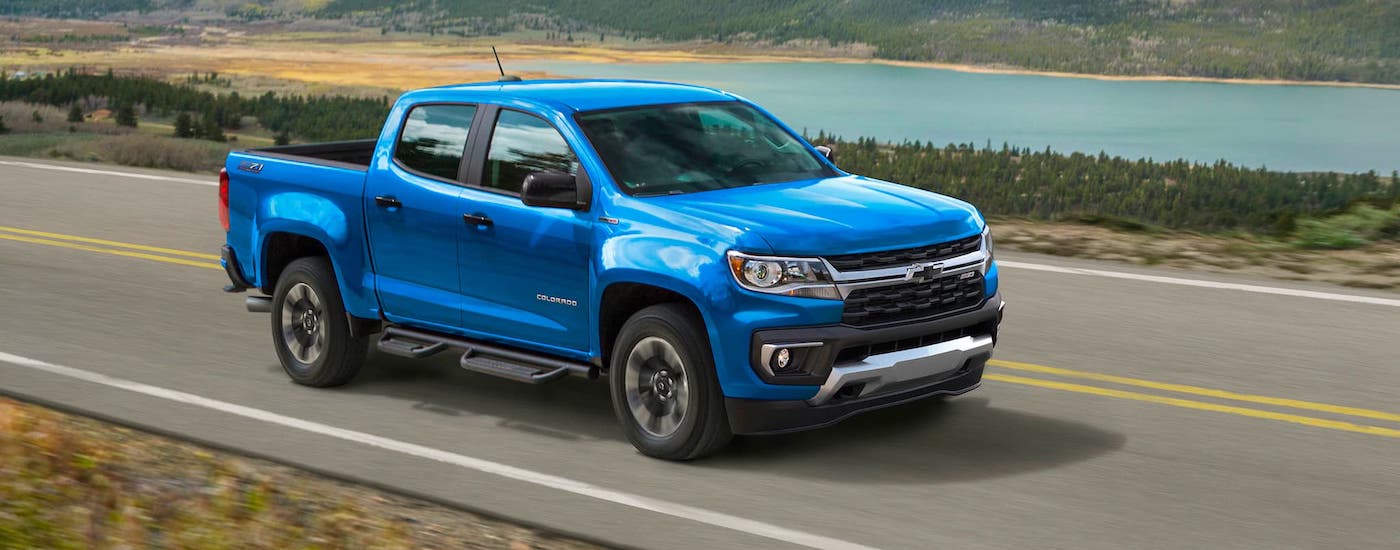 A blue 2021 Chevy Colorado is driving on a road overlooking a river.