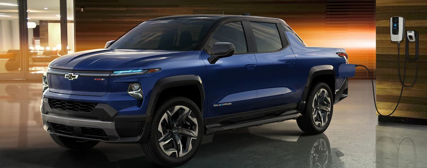A blue 2024 Chevy Silverado EV is parked at a charging station.