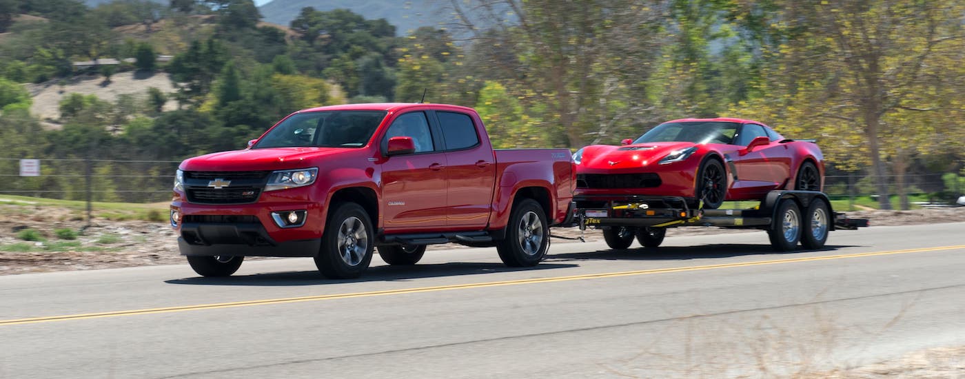 A red 2016 Chevy Colorado is towing a red Chevy Corvette.