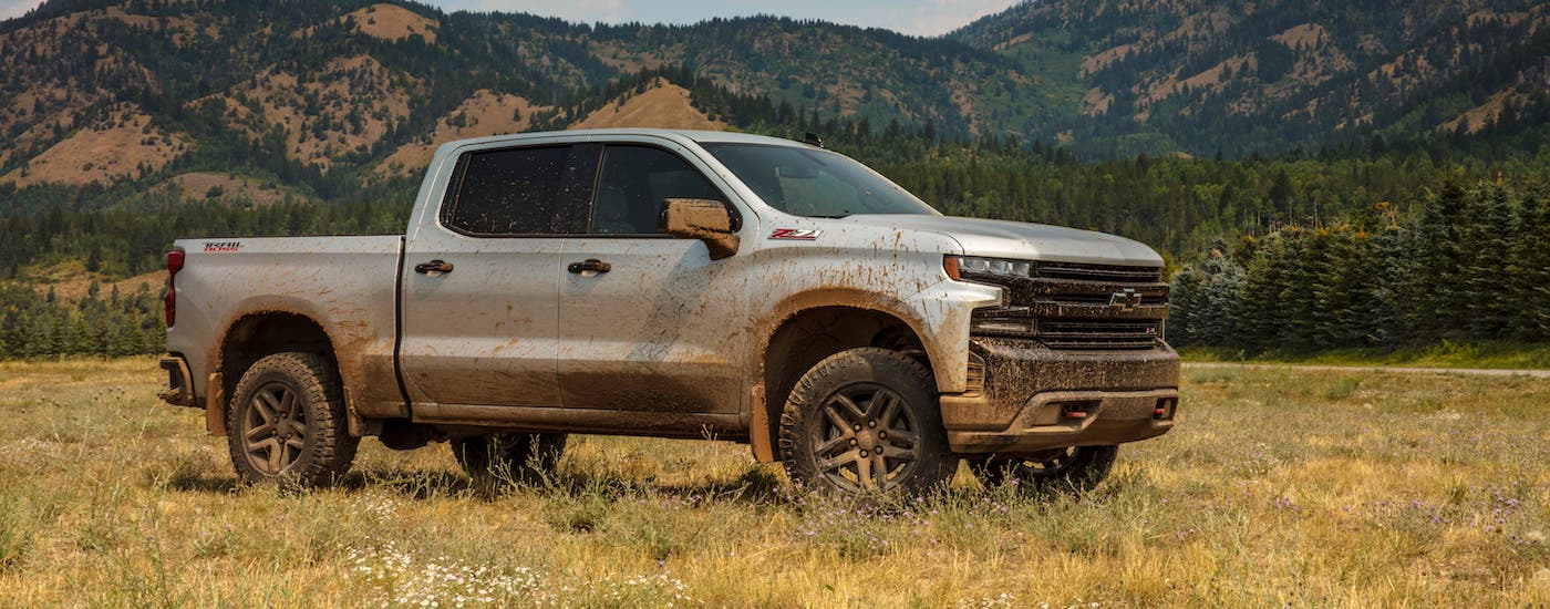 A muddy silver 2019 Chevy Silverado 1500 TrailBoss is parked in a field.