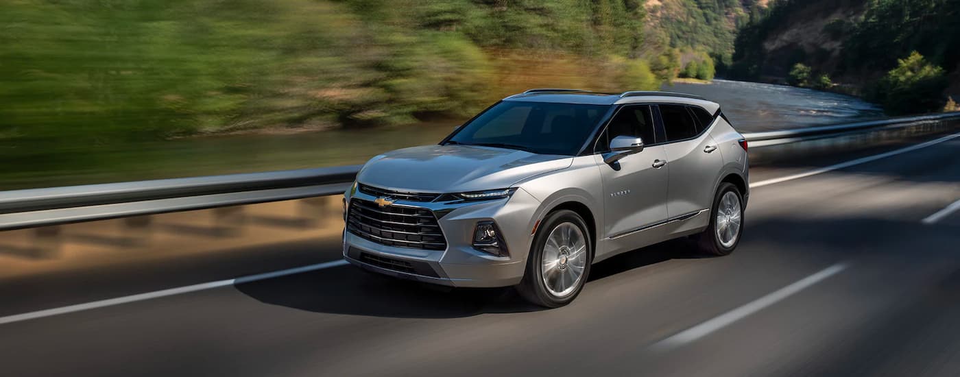 A silver 2021 Chevy Blazer is shown from the side driving past a lake.