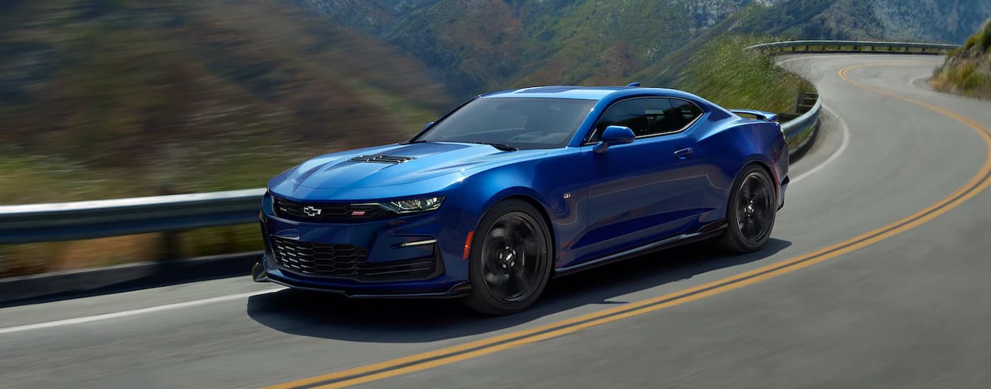 A blue 2021 Chevy Camaro 2SS is shown from the side driving down a winding road.
