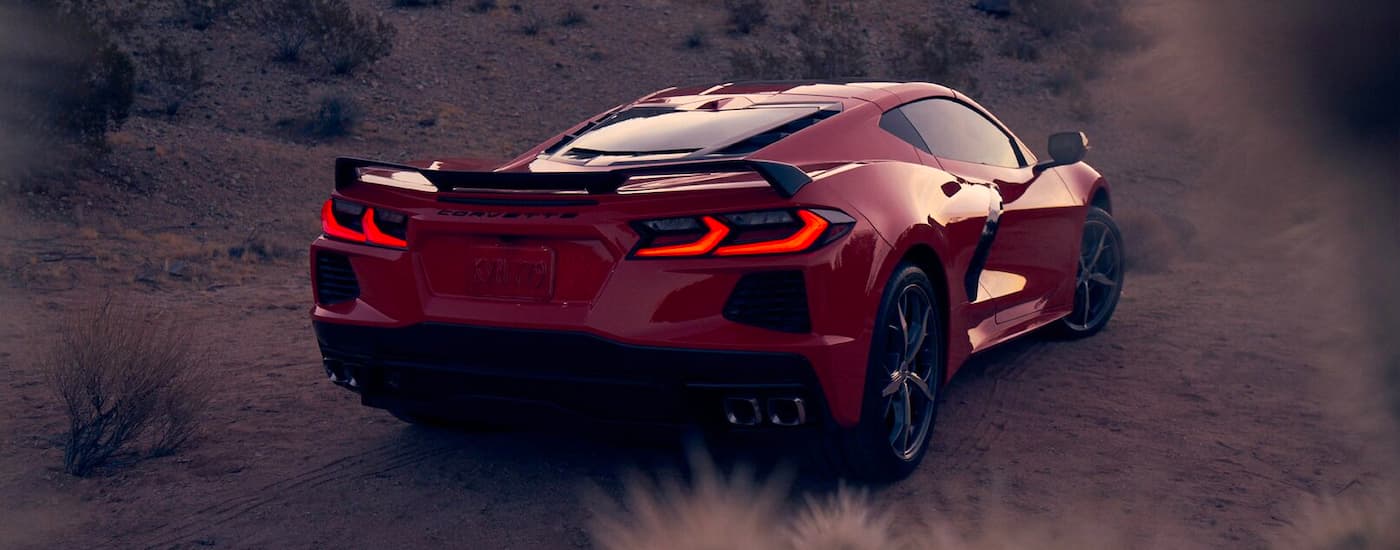 An orange 2021 Chevy Corvette Stingray is shown from the rear parked on the dirt.