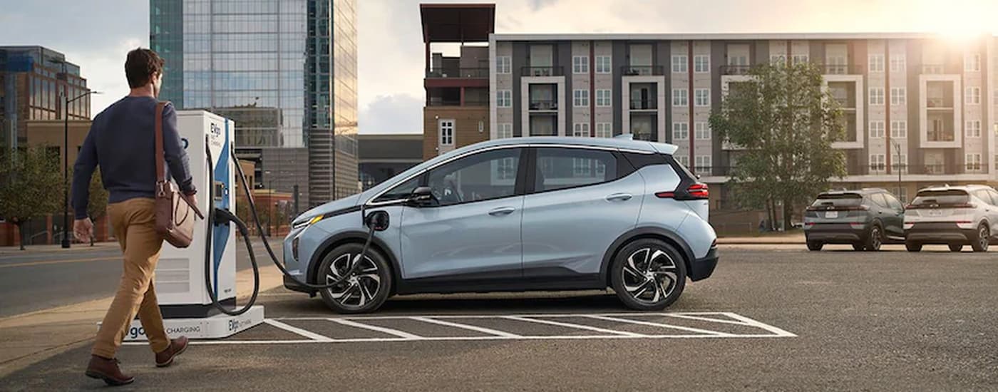 A light blue 2022 Chevy Bolt EV is shown charging after visiting a Tomball car dealership.