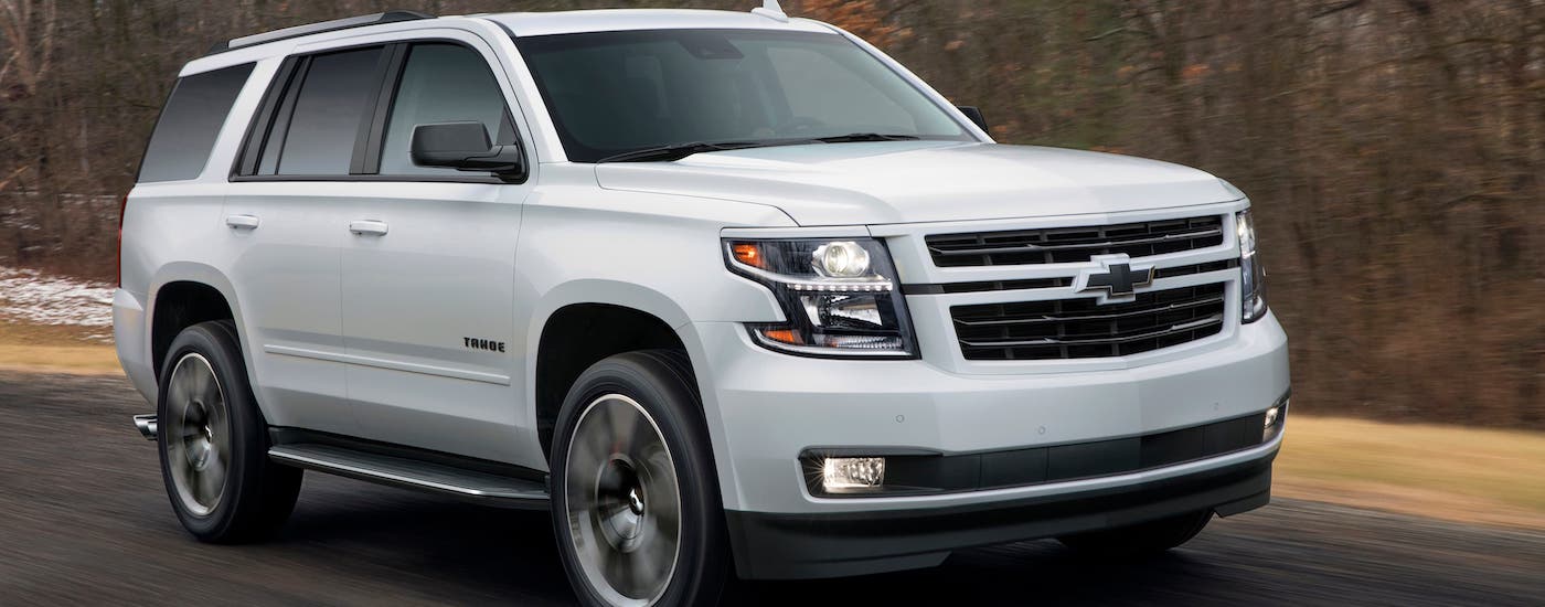 A white 2018 Chevy Tahoe RST from a used Chevy dealer in Houston is driving on a road.