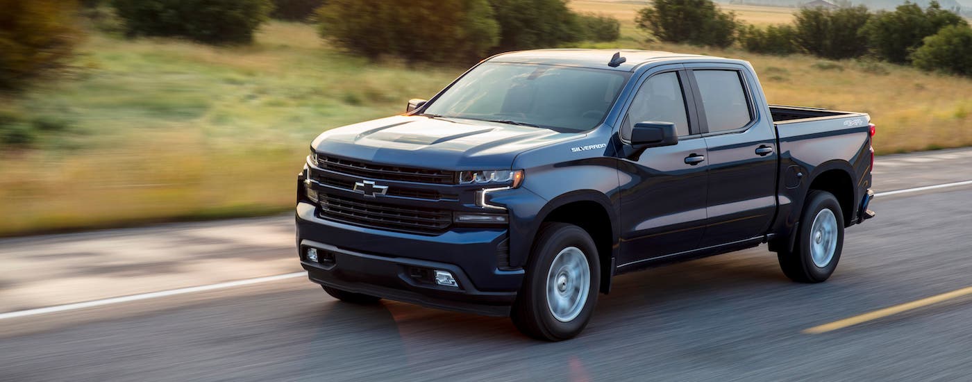 A blue 2019 Chevy Silverado RST is driving on an empty highway.