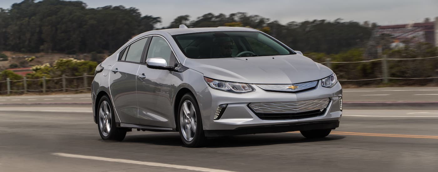 A silver 2017 Chevy Volt EV is driving on an empty highway.