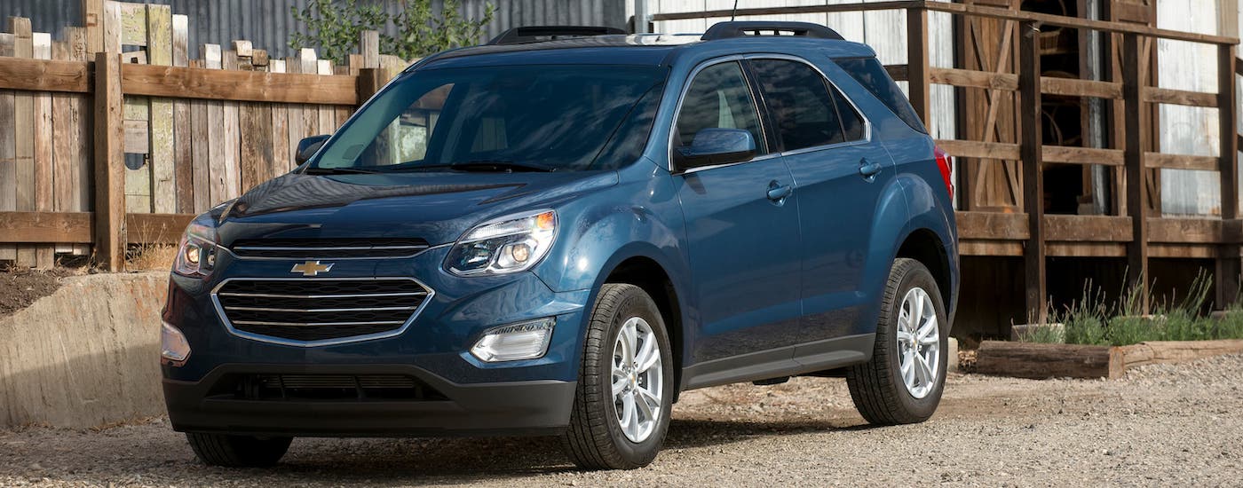 A blue 2017 Chevy Equinox is shown parked in front of a wooden farm building.