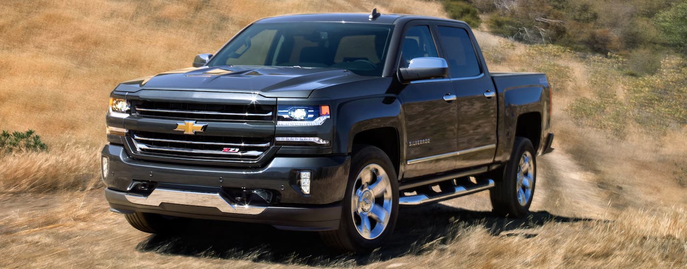 A black 2018 used Chevy Silverado Z71 is shown driving on a dirt road.