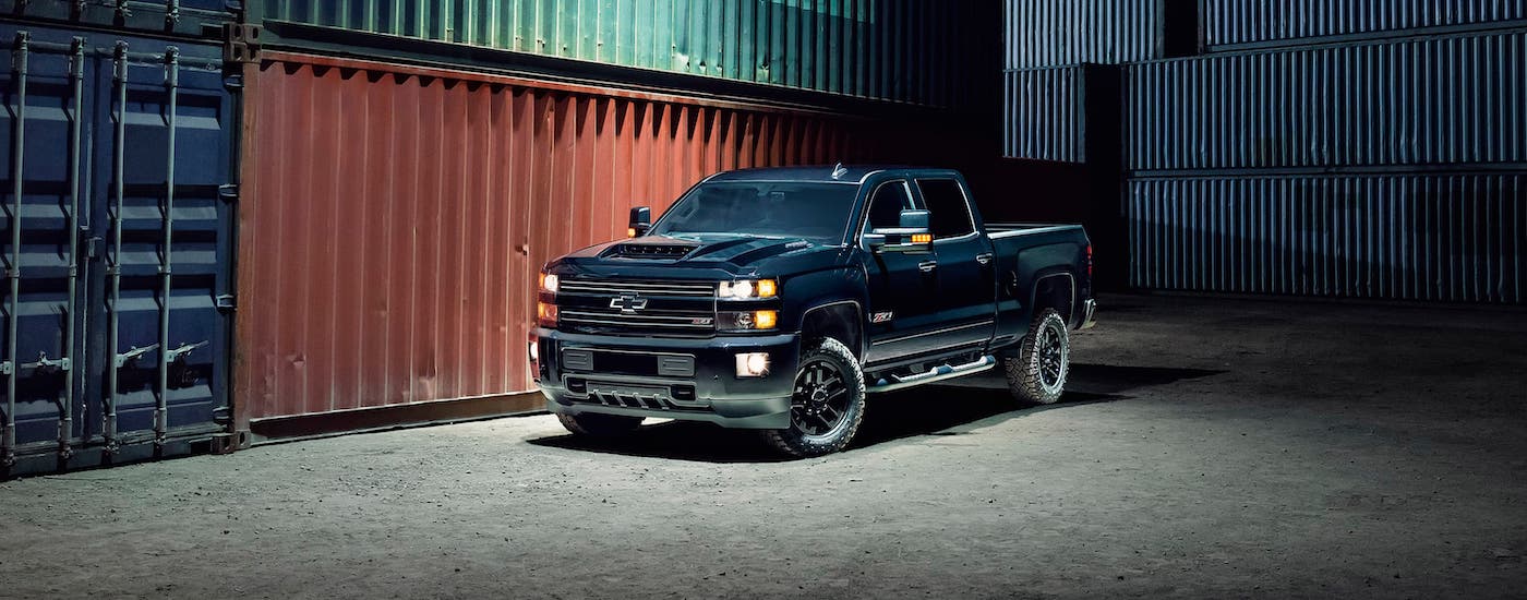 A black 2017 used Chevy Silverado 2500 Z71 is parked in front of shipping containers at night.