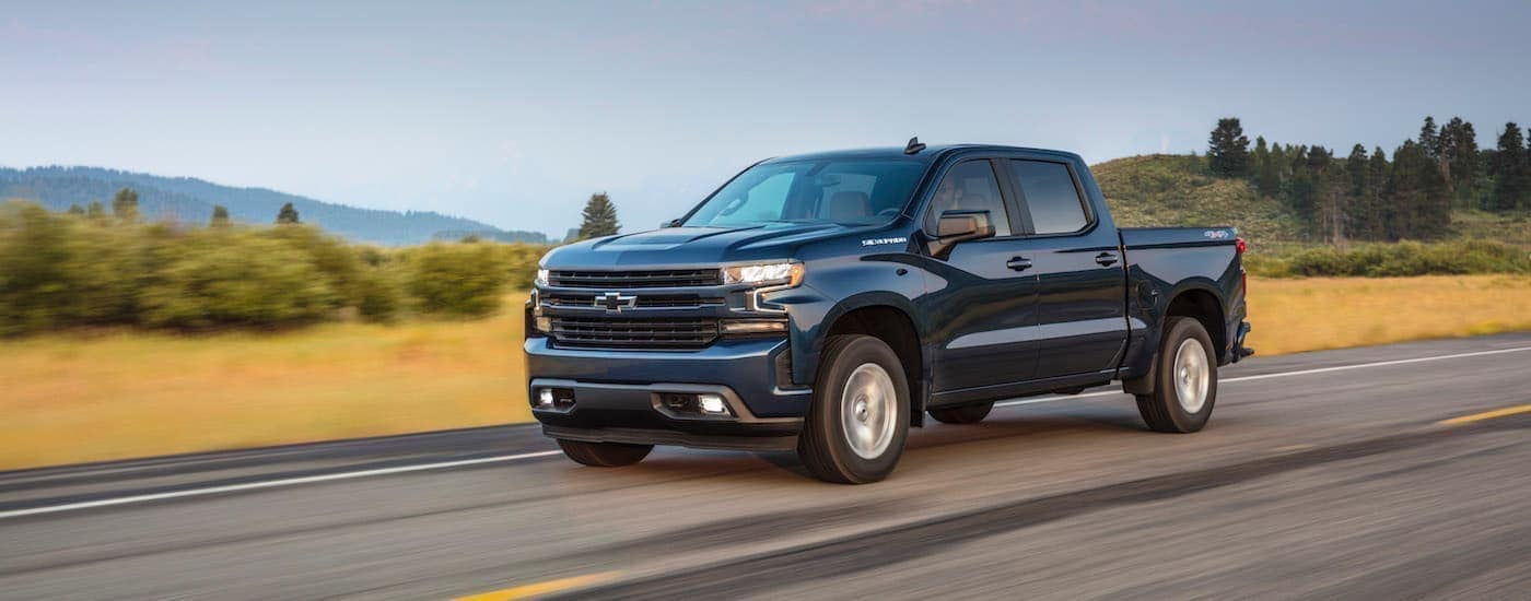A blue 2020 Chevy Silverado 1500 is shown driving on an open road.