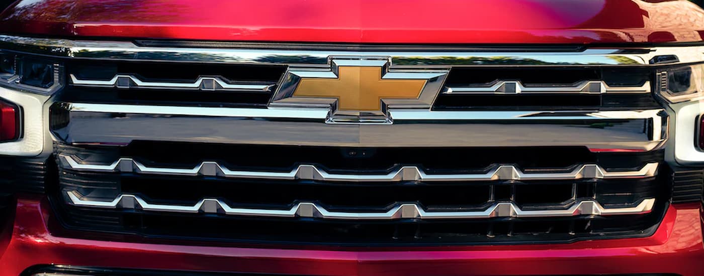 A close up of the grille and badge on a red used 2022 Chevy Silverado 1500 for sale is shown.