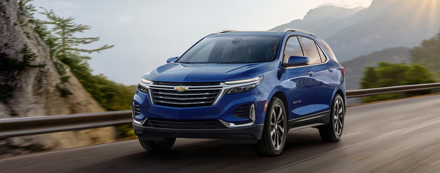 A blue 2022 Chevy Equinox Premier is shown from a front angle driving on a mountain highway.